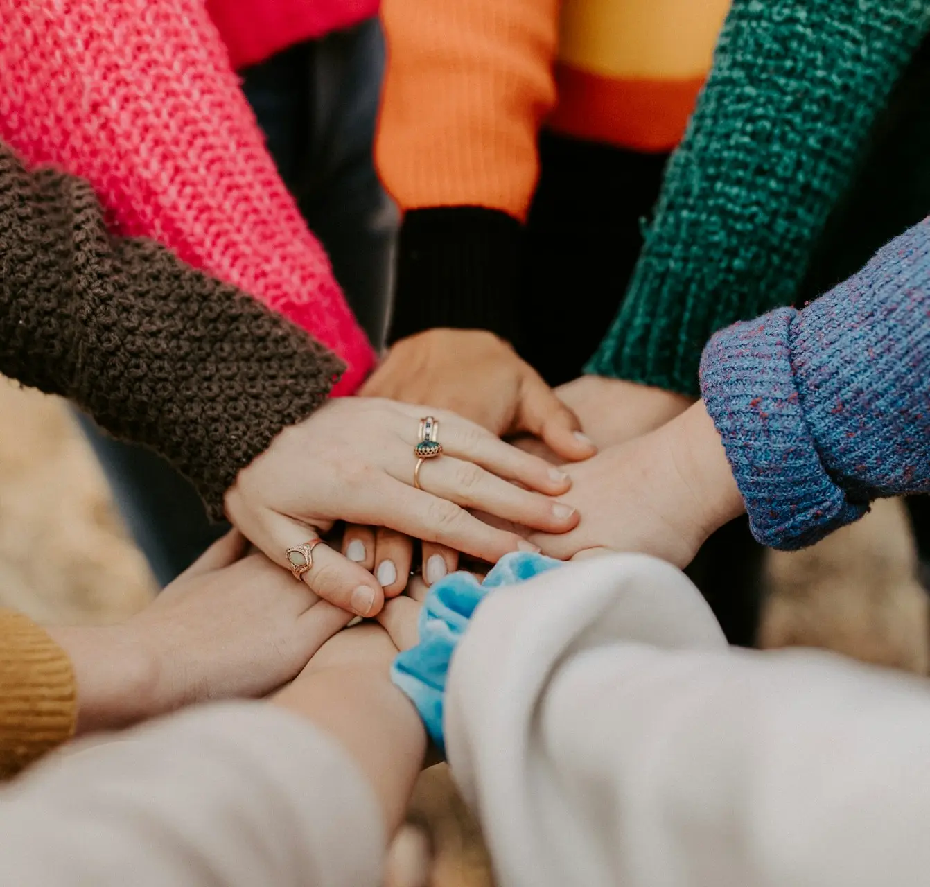 person in red sweater holding babys hand